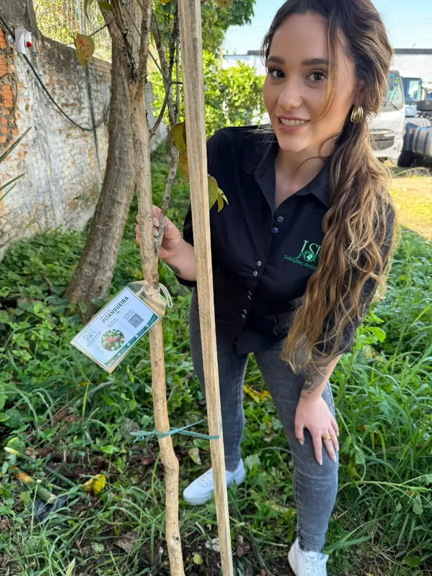 Especialista da JSR ao lado de muda de espécie nativa com a plaqueta de rastreabilidade