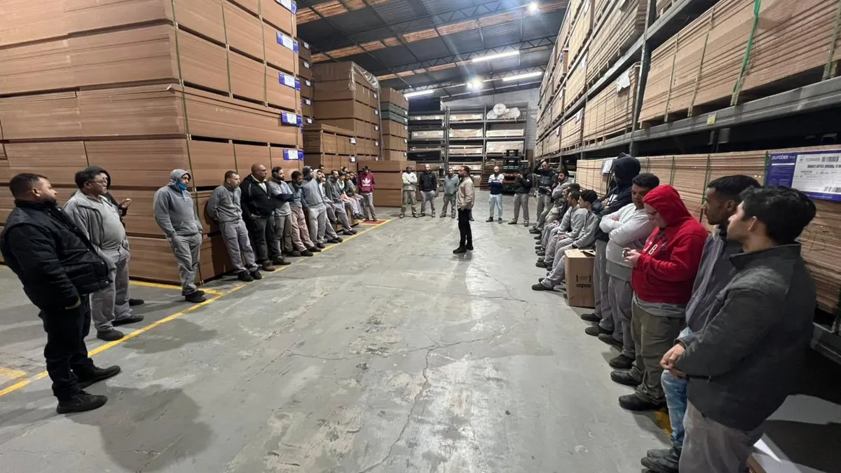 Treinamento ambiental em roda com a equipe operacional em galpão
