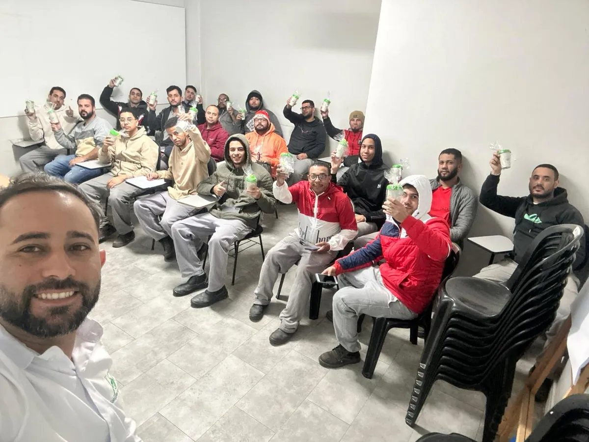Turma em treinamento de conscientização ambiental erguendo as mudas recebidas da JSR
